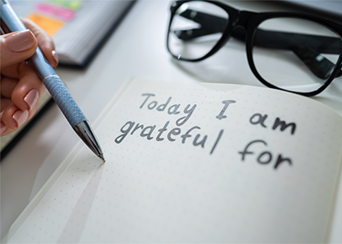 journal on desk with glasses and woman writing today ia ma grateful for to be set for blog post image